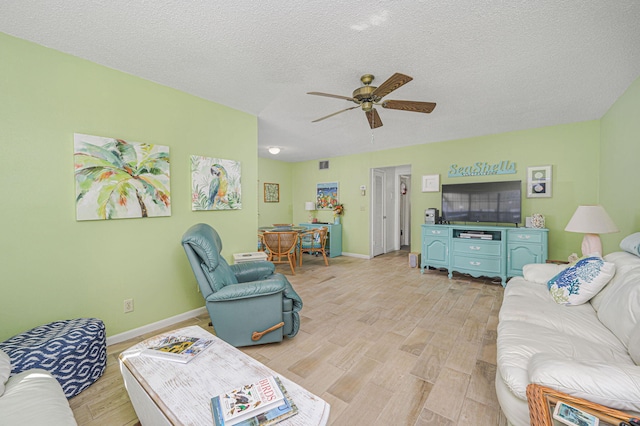 living room with ceiling fan, light hardwood / wood-style floors, and a textured ceiling