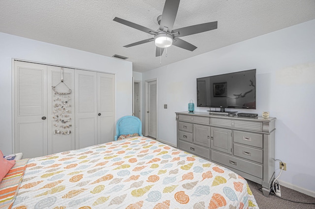 bedroom featuring a textured ceiling, light colored carpet, ceiling fan, and multiple closets