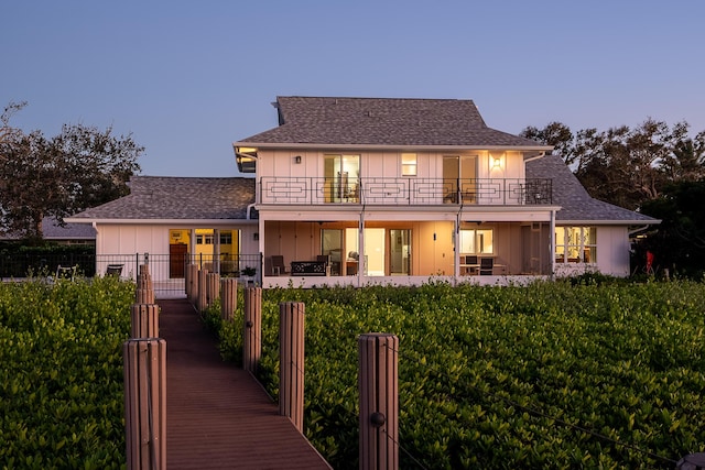 back house at dusk featuring a balcony