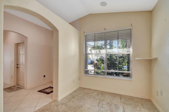 empty room featuring light tile patterned floors and vaulted ceiling