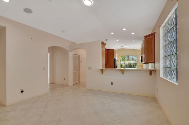 unfurnished room featuring light tile patterned floors and vaulted ceiling