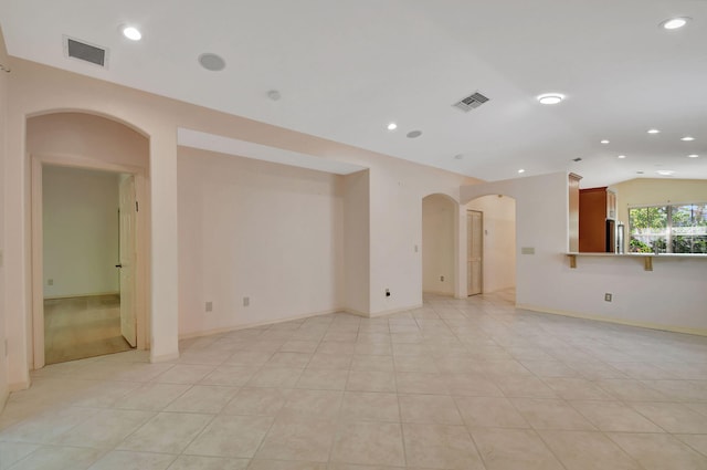 spare room featuring vaulted ceiling and light tile patterned flooring