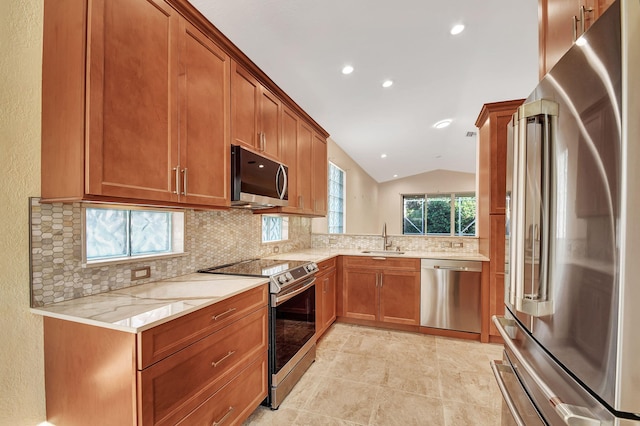 kitchen with tasteful backsplash, light stone counters, stainless steel appliances, sink, and lofted ceiling