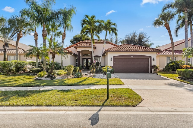 mediterranean / spanish house featuring a front yard, french doors, and a garage