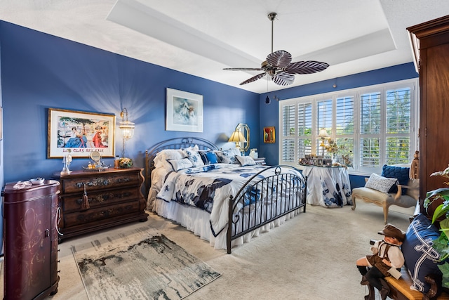 bedroom with a tray ceiling, ceiling fan, and light colored carpet