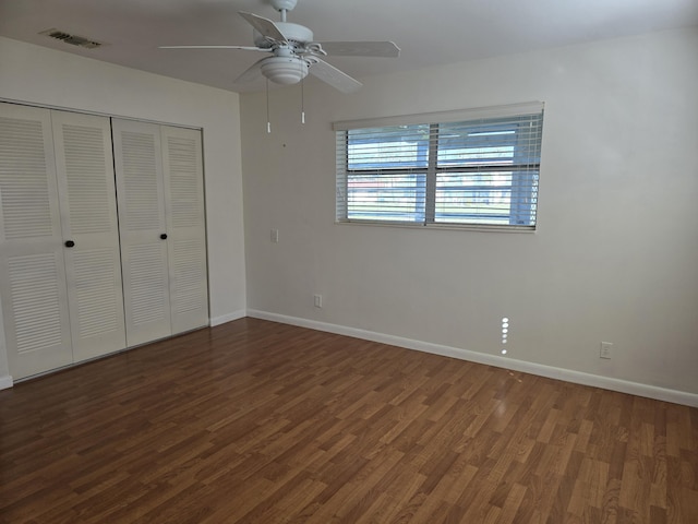 unfurnished bedroom with ceiling fan, dark wood-type flooring, and a closet