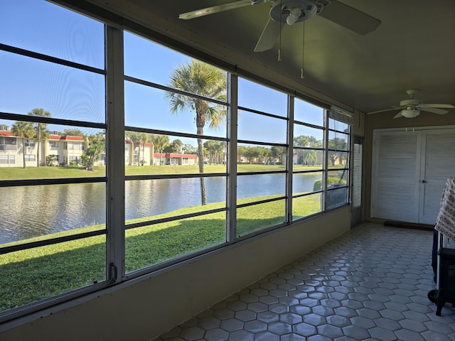 unfurnished sunroom featuring a water view and ceiling fan