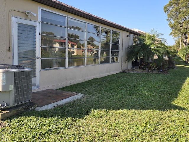 view of side of home with central air condition unit and a lawn