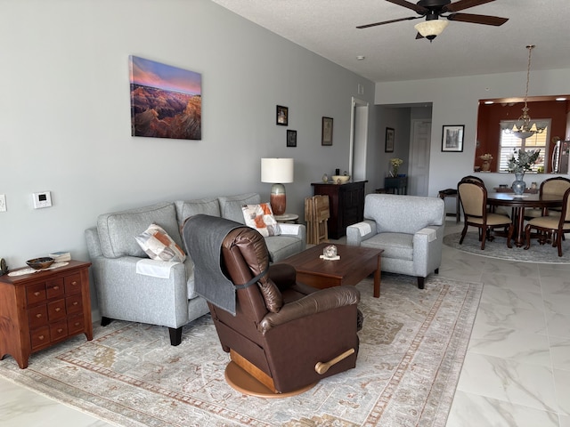 living room featuring ceiling fan with notable chandelier and a textured ceiling