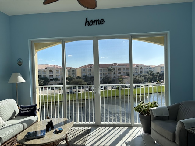 tiled living room featuring a water view, plenty of natural light, and ceiling fan