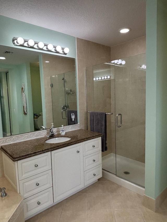 bathroom featuring a textured ceiling, vanity, tile patterned floors, and walk in shower