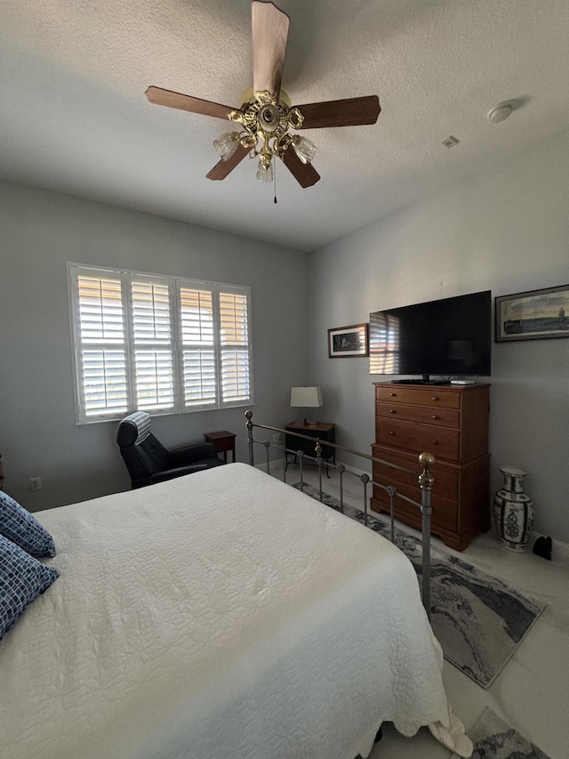 bedroom with ceiling fan and a textured ceiling