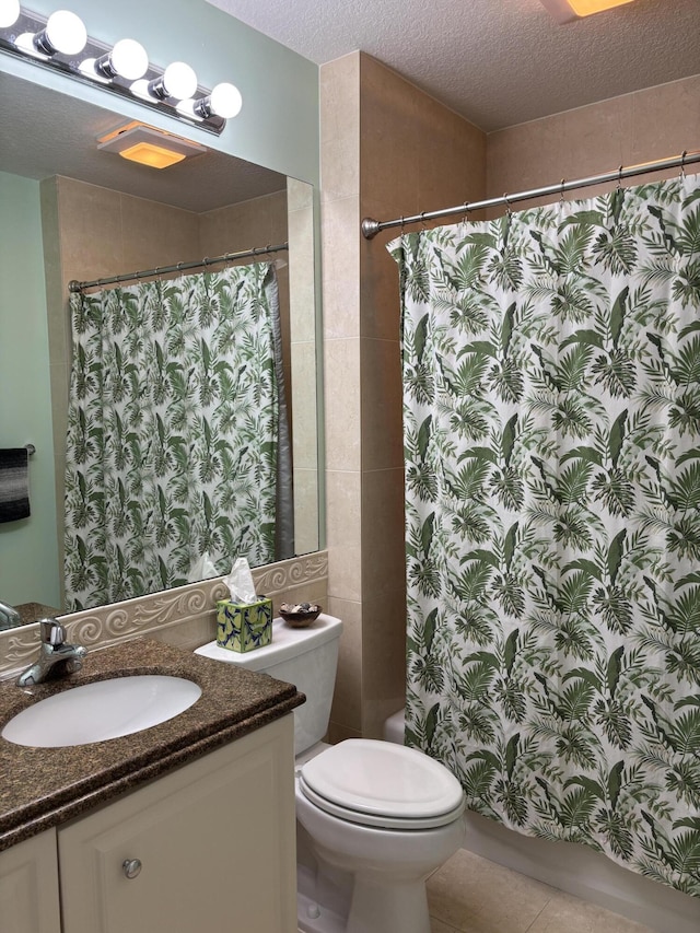 bathroom with tile patterned floors, vanity, a textured ceiling, toilet, and curtained shower