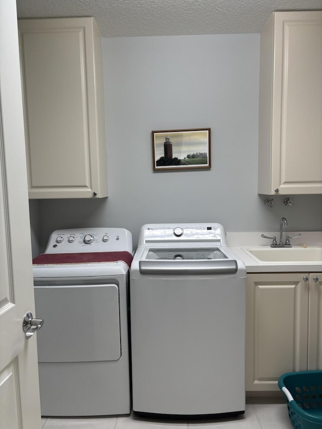 washroom featuring cabinets, a textured ceiling, sink, light tile patterned floors, and independent washer and dryer