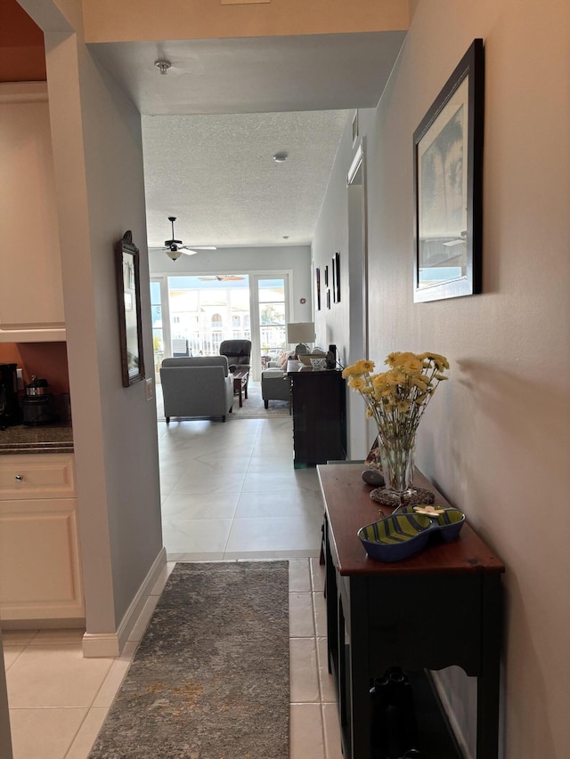 hallway featuring light tile patterned flooring and a textured ceiling