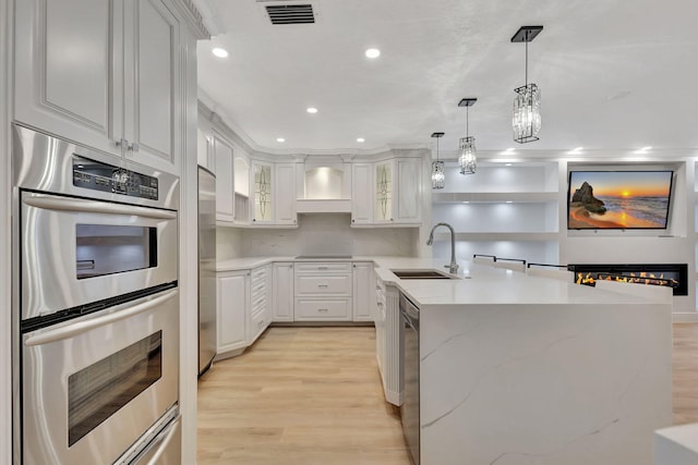 kitchen featuring hanging light fixtures, sink, light hardwood / wood-style flooring, double oven, and white cabinetry