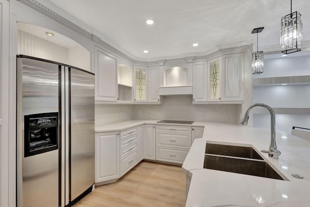 kitchen featuring stainless steel refrigerator with ice dispenser, custom exhaust hood, black electric cooktop, decorative light fixtures, and white cabinets