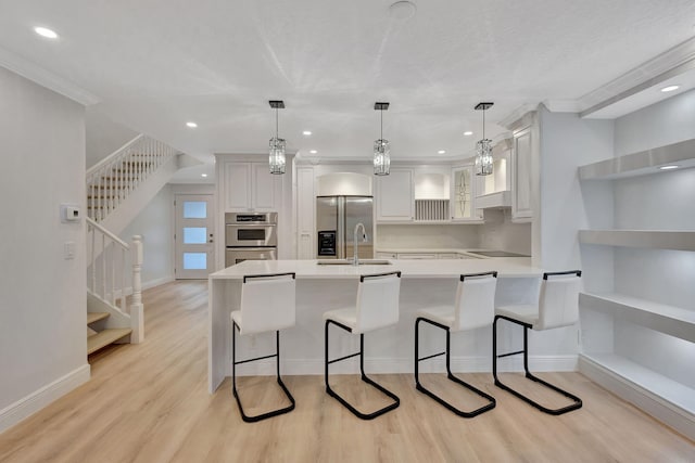 kitchen with white cabinets, a breakfast bar, stainless steel appliances, and decorative light fixtures