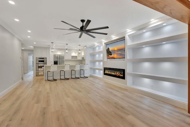 unfurnished living room with light wood-type flooring, built in features, ceiling fan, and ornamental molding