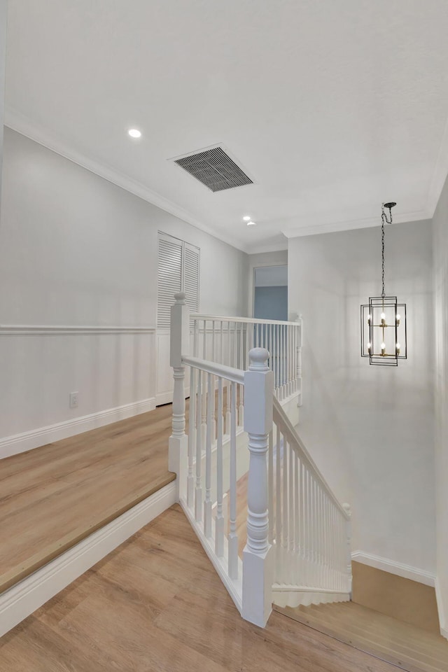 hall featuring crown molding, light hardwood / wood-style flooring, and a chandelier