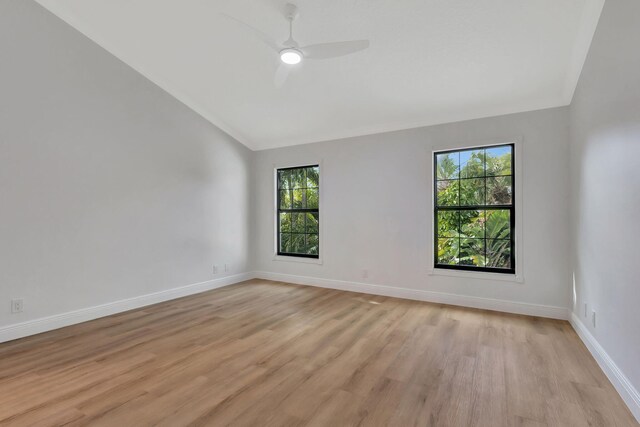 empty room with ceiling fan, light hardwood / wood-style flooring, and vaulted ceiling