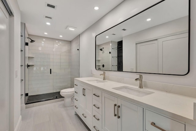 bathroom with a shower with door, vanity, and toilet