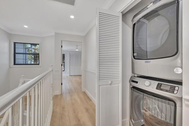 laundry area with light hardwood / wood-style floors, crown molding, and stacked washer and dryer