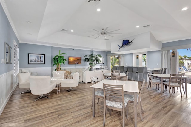 dining room featuring a raised ceiling, light hardwood / wood-style flooring, ceiling fan, and ornamental molding