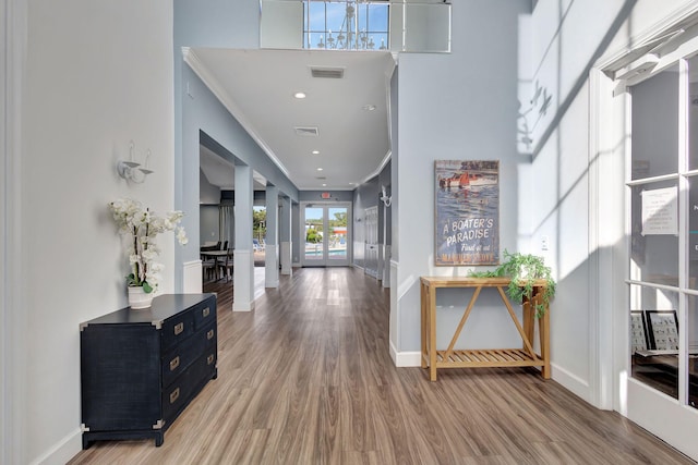 foyer entrance with wood-type flooring, french doors, and ornamental molding