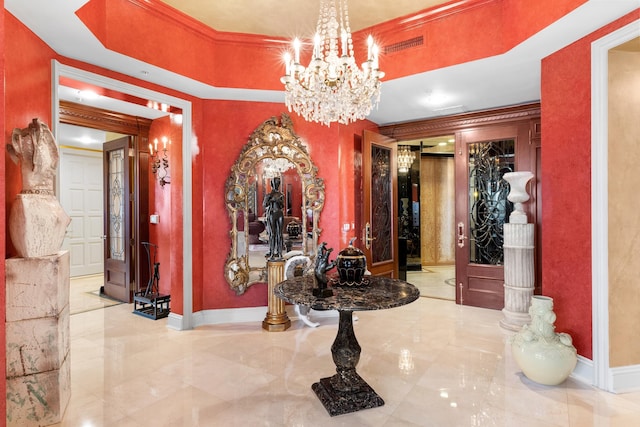 interior space with a chandelier, a raised ceiling, crown molding, and ornate columns