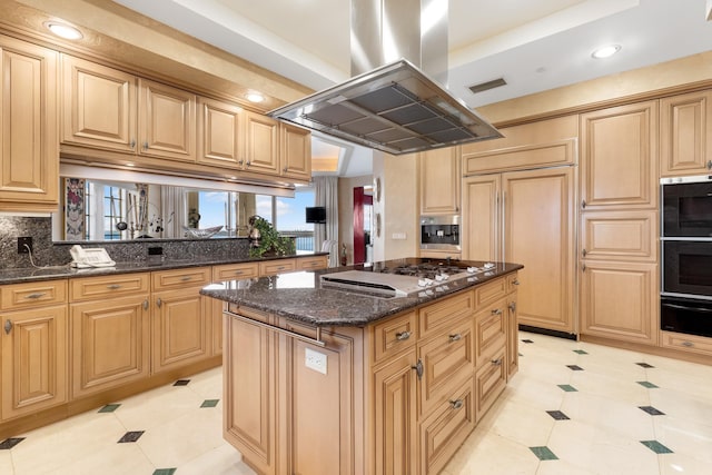 kitchen with a center island, paneled built in fridge, dark stone countertops, stainless steel gas stovetop, and island range hood