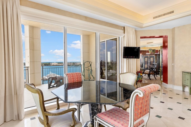 tiled dining space with a tray ceiling, floor to ceiling windows, and ornamental molding