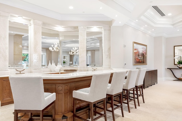 bar with ornate columns, an inviting chandelier, and ornamental molding