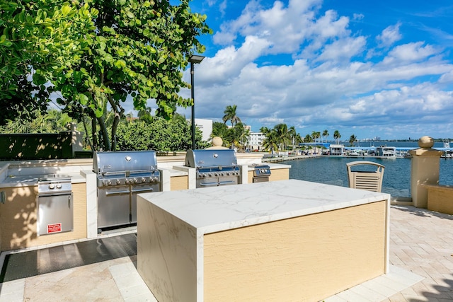 view of patio / terrace with a grill, a water view, and an outdoor kitchen