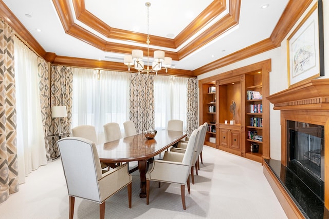 dining area with a raised ceiling, built in shelves, light colored carpet, and an inviting chandelier