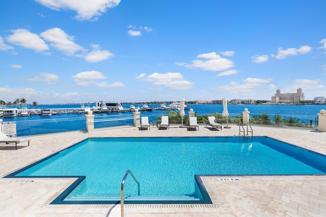 view of pool featuring a water view and a patio