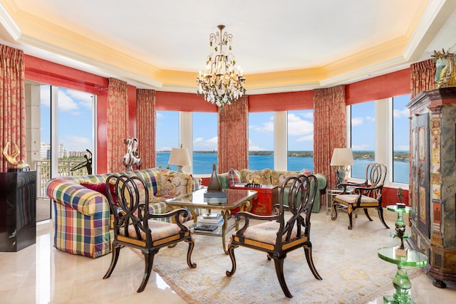 dining room with a tray ceiling, a water view, a healthy amount of sunlight, and an inviting chandelier