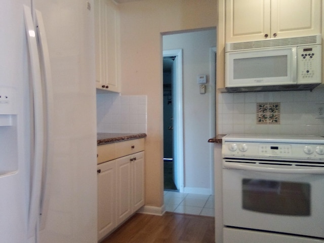 kitchen with backsplash, white cabinetry, wood finished floors, white appliances, and baseboards