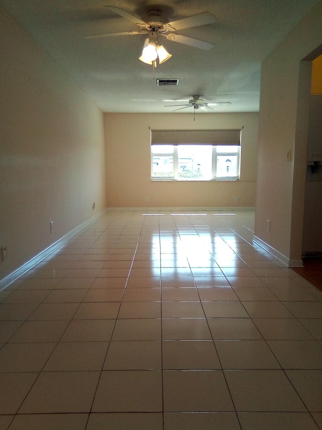 tiled spare room with ceiling fan