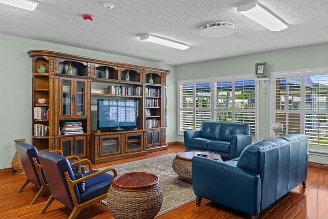 sitting room with a textured ceiling, baseboards, and wood finished floors