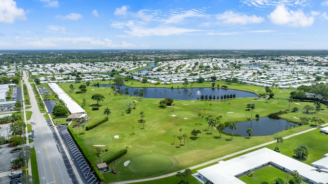 drone / aerial view with golf course view and a water view