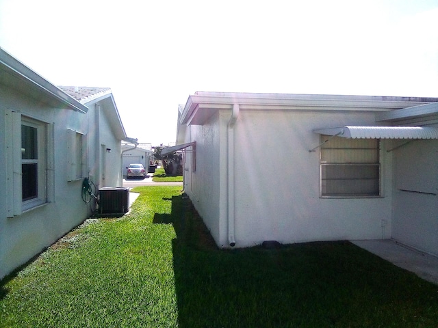 view of home's exterior featuring stucco siding, cooling unit, and a yard