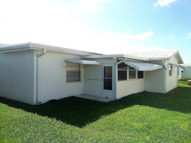 back of property featuring a yard and stucco siding