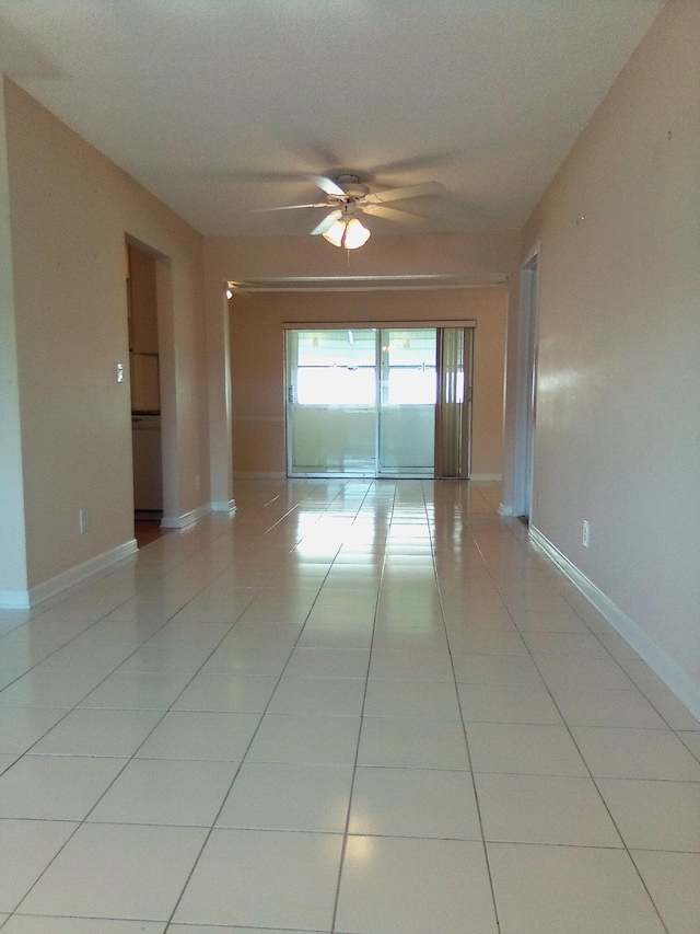 empty room featuring light tile patterned floors, ceiling fan, and baseboards