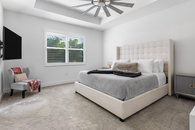 carpeted bedroom with ceiling fan and a tray ceiling