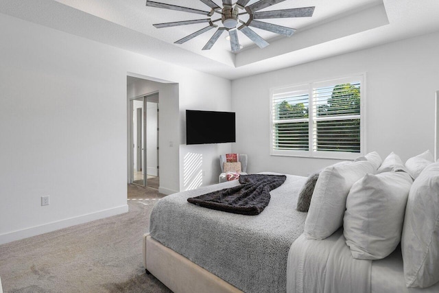 bedroom featuring carpet flooring, a raised ceiling, and ceiling fan