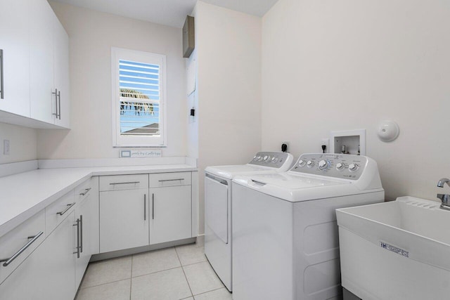 laundry room featuring cabinets, light tile patterned floors, sink, and washing machine and clothes dryer