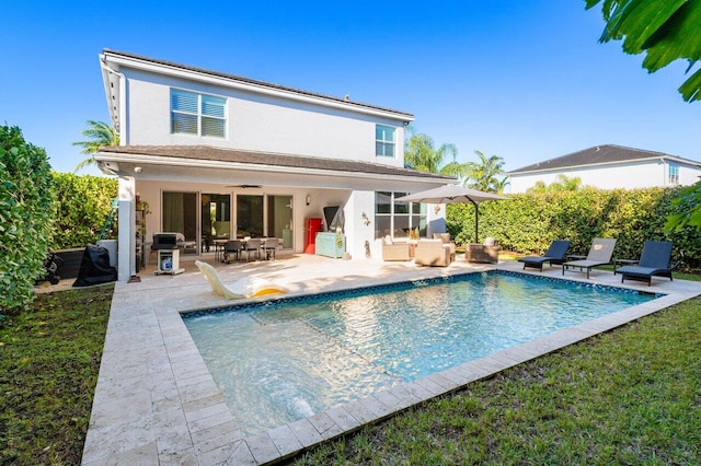 rear view of property featuring outdoor lounge area, a fenced in pool, ceiling fan, and a patio area