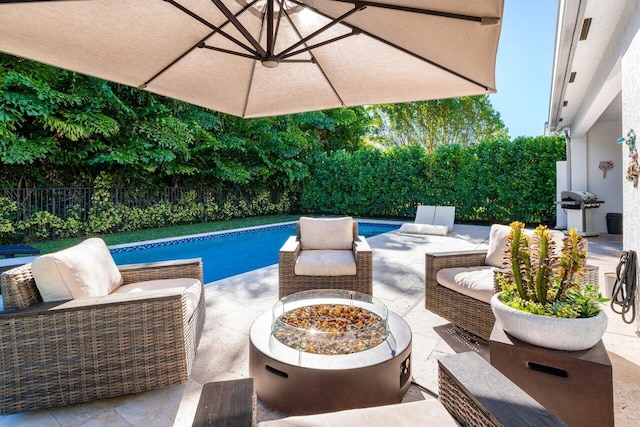 view of swimming pool with a patio area, grilling area, and an outdoor living space with a fire pit