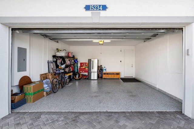 garage with electric panel, a garage door opener, and stainless steel refrigerator